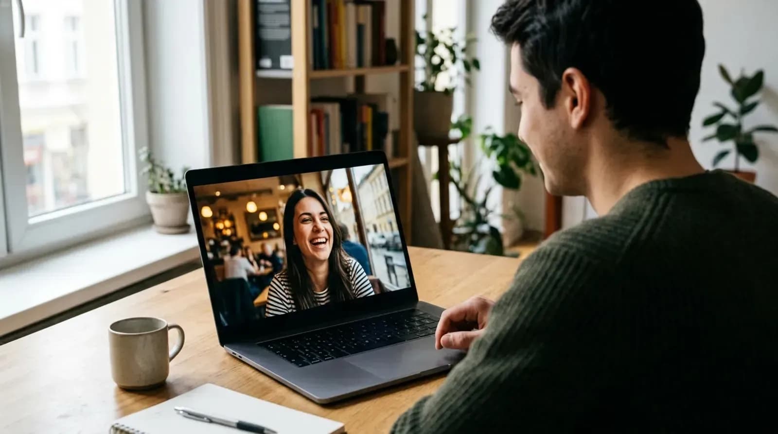 A young man on a laptop smiling during a random video chat with a stranger