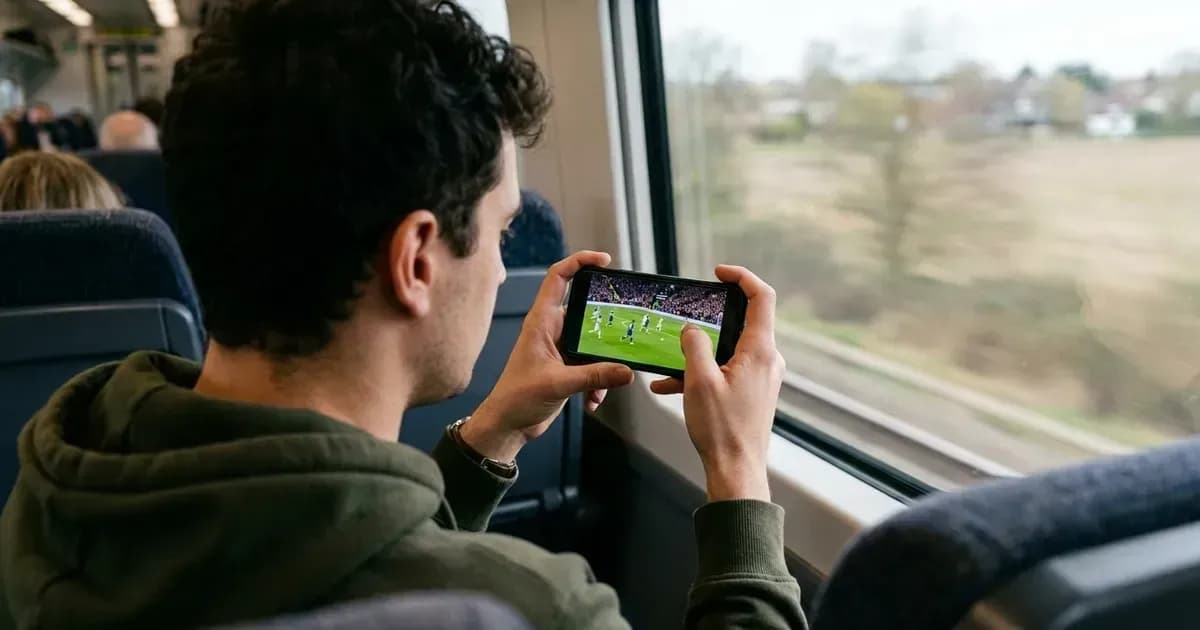 Un spectateur regarde un match de football en streaming sur son téléphone dans un train